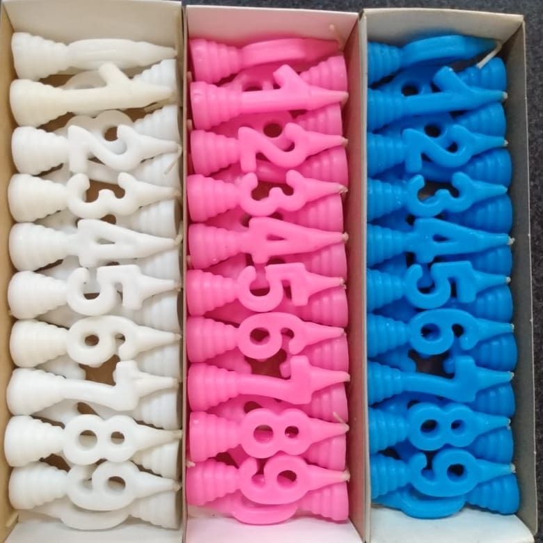 Cajas de velas de cumpleaños con forma de números: blanco, rosa y azul, ordenados del 0 al 9.