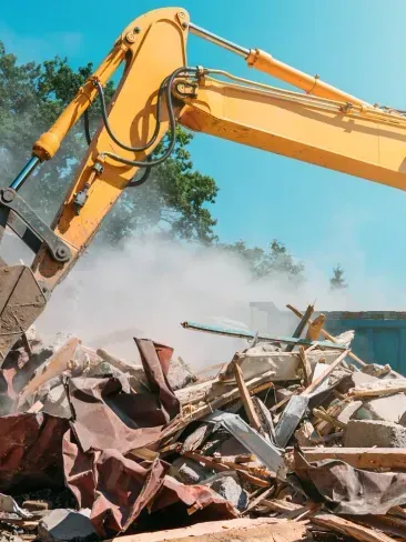A yellow excavator is demolishing a building.