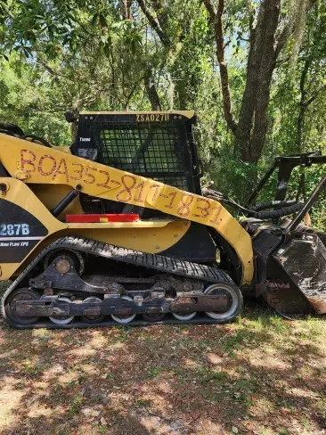 A bulldozer is parked in the grass in the woods.
