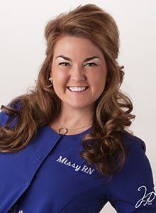 A woman is wearing a blue jacket and smiling for the camera.