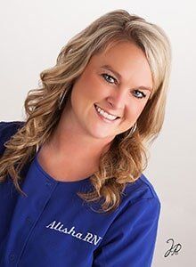 A woman is wearing a blue scrub and smiling for the camera.