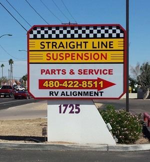 Sign for Straight Line Suspension, offering parts, service, and RV alignment, with phone number, set along a street.