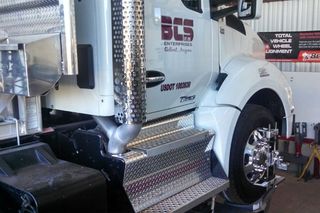 White semi-truck with chrome detailing being serviced. 