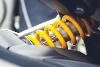 Yellow coil spring shock absorber on a vehicle, close-up.