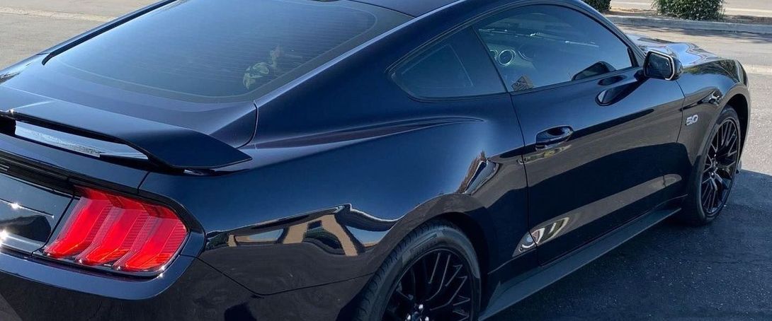 A black ford mustang is parked in a parking lot.