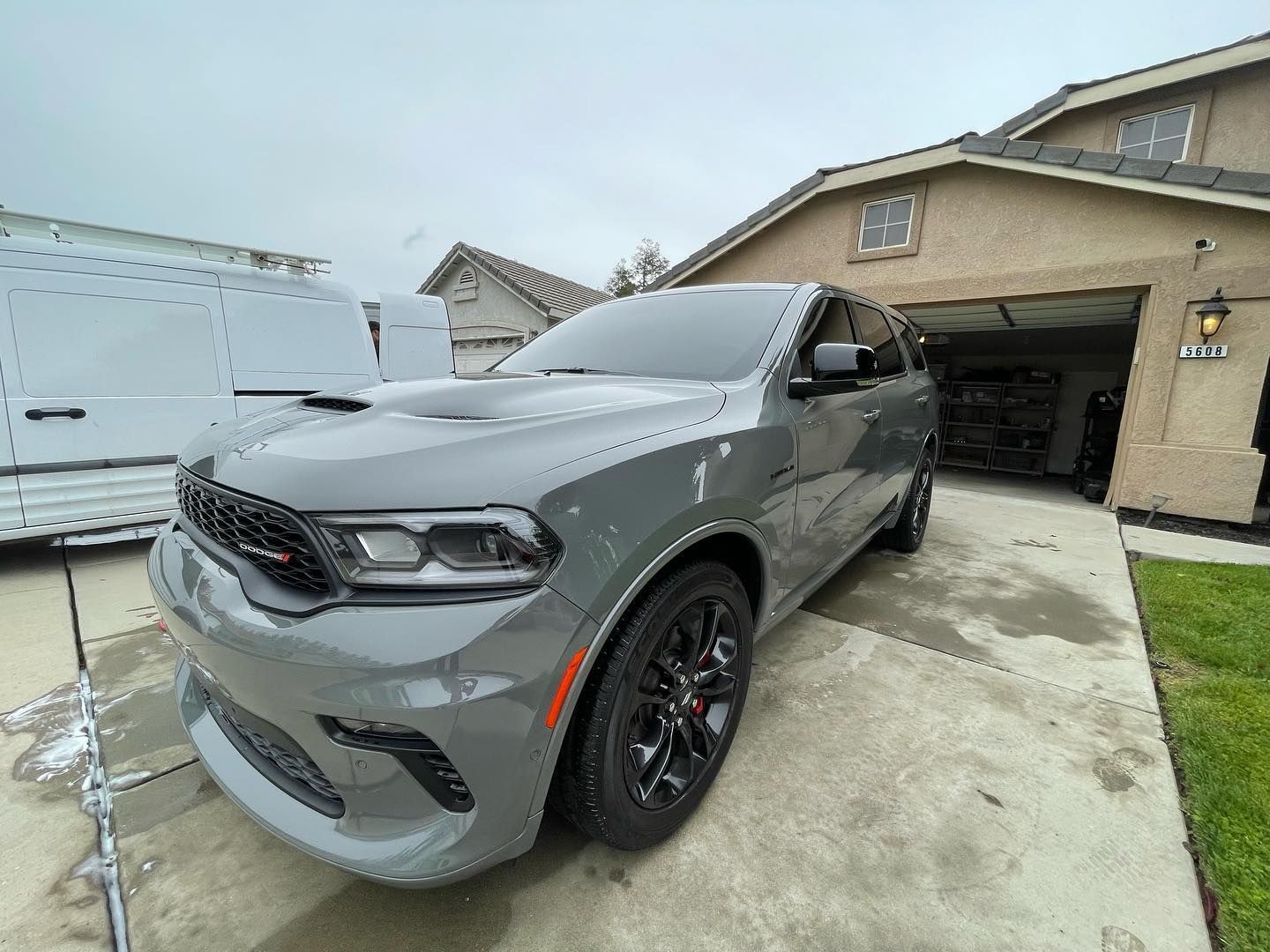 A gray dodge durango is parked in a driveway in front of a house.