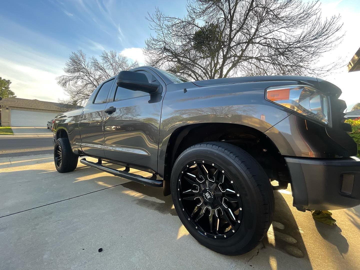A black truck is parked on gravel next to a road.