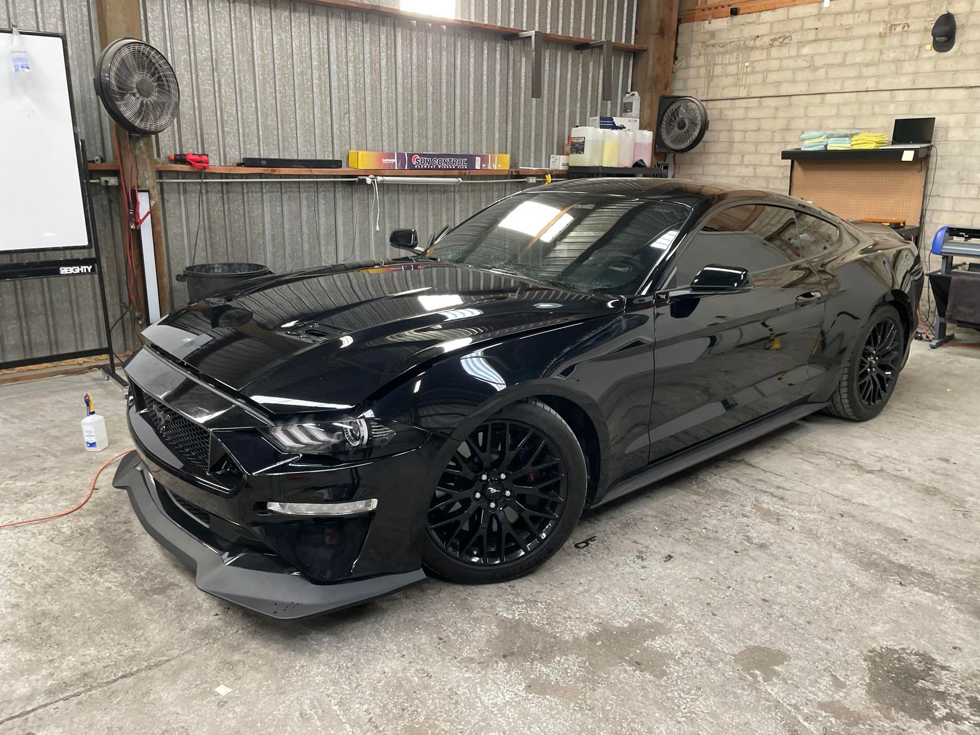 A black truck is parked on gravel next to a road.
