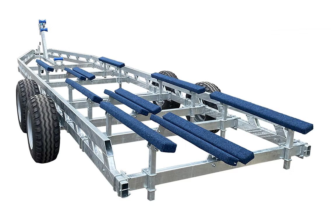 A silver boat trailer with blue padded bunks and two sets of tires.