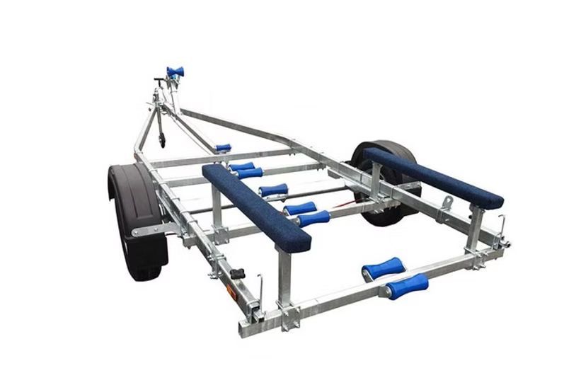 Boat trailer, silver frame, black tires, blue rollers and bunk supports, white background.
