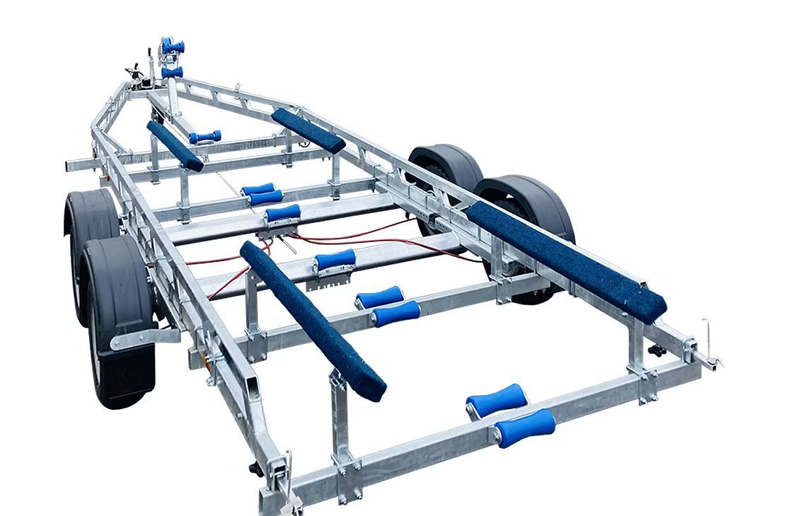A silver boat trailer with multiple blue rollers and tires, on a white background.