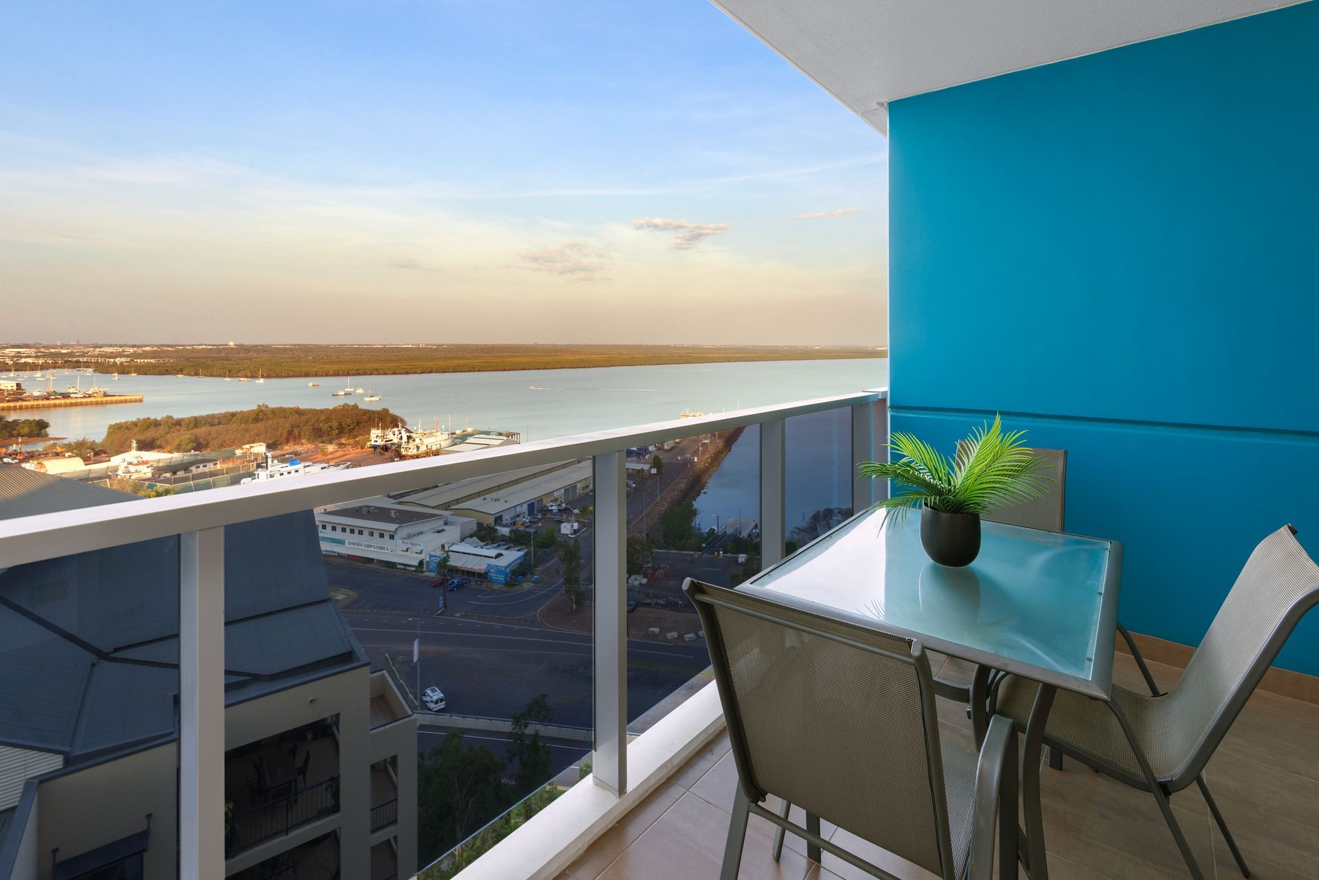 A balcony with a table and chairs overlooking a body of water.