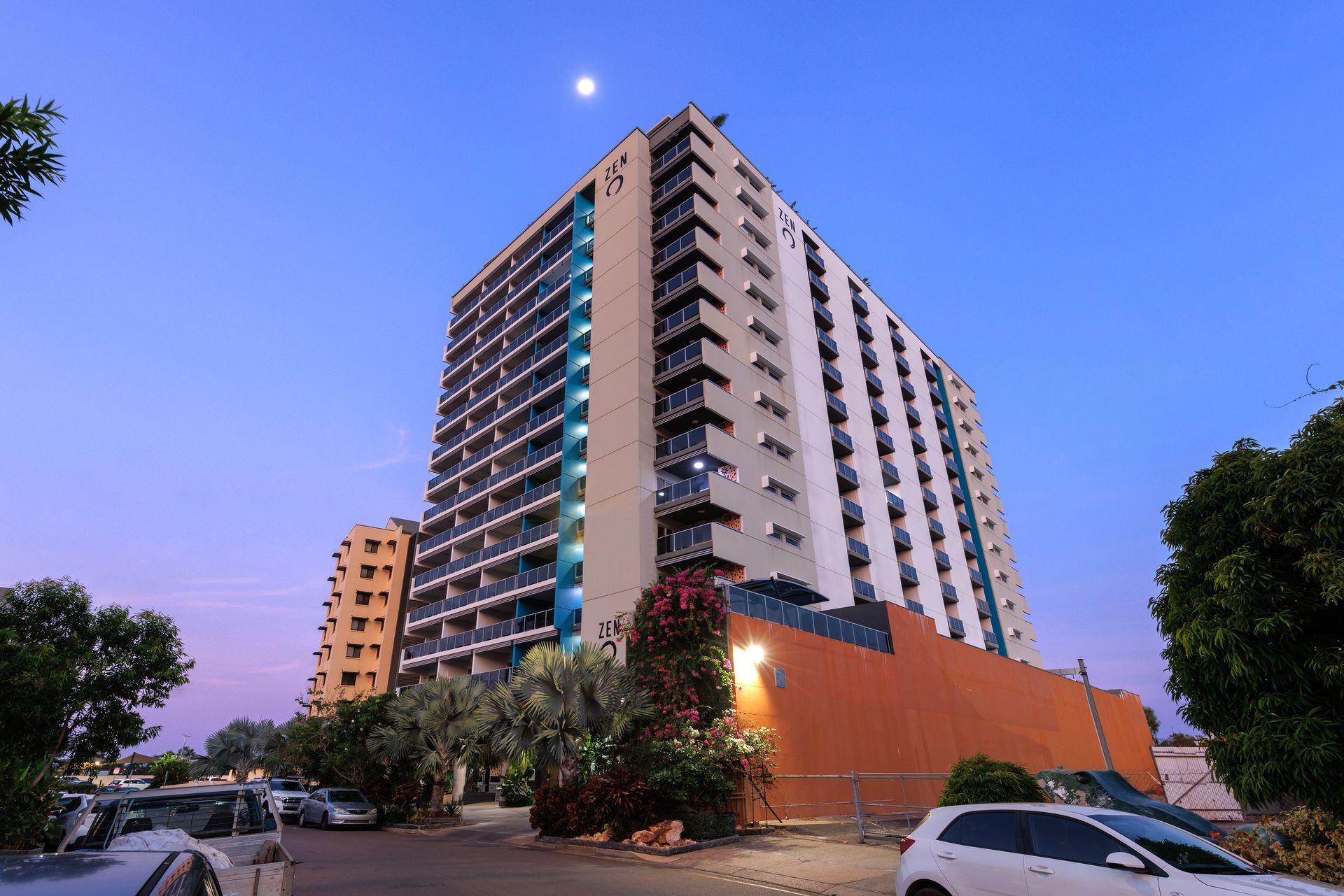 A tall building with cars parked in front of it at night.