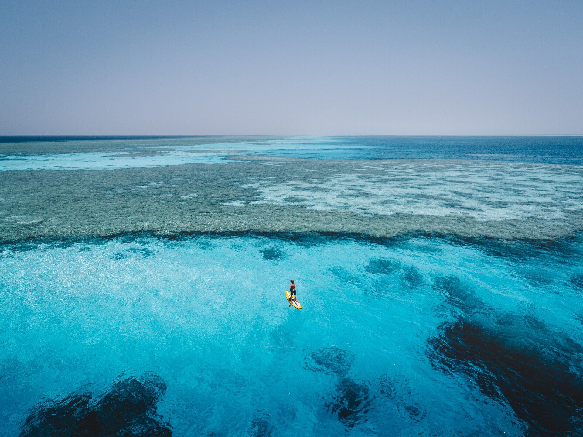 An aerial view of a person riding a surfboard in the ocean.