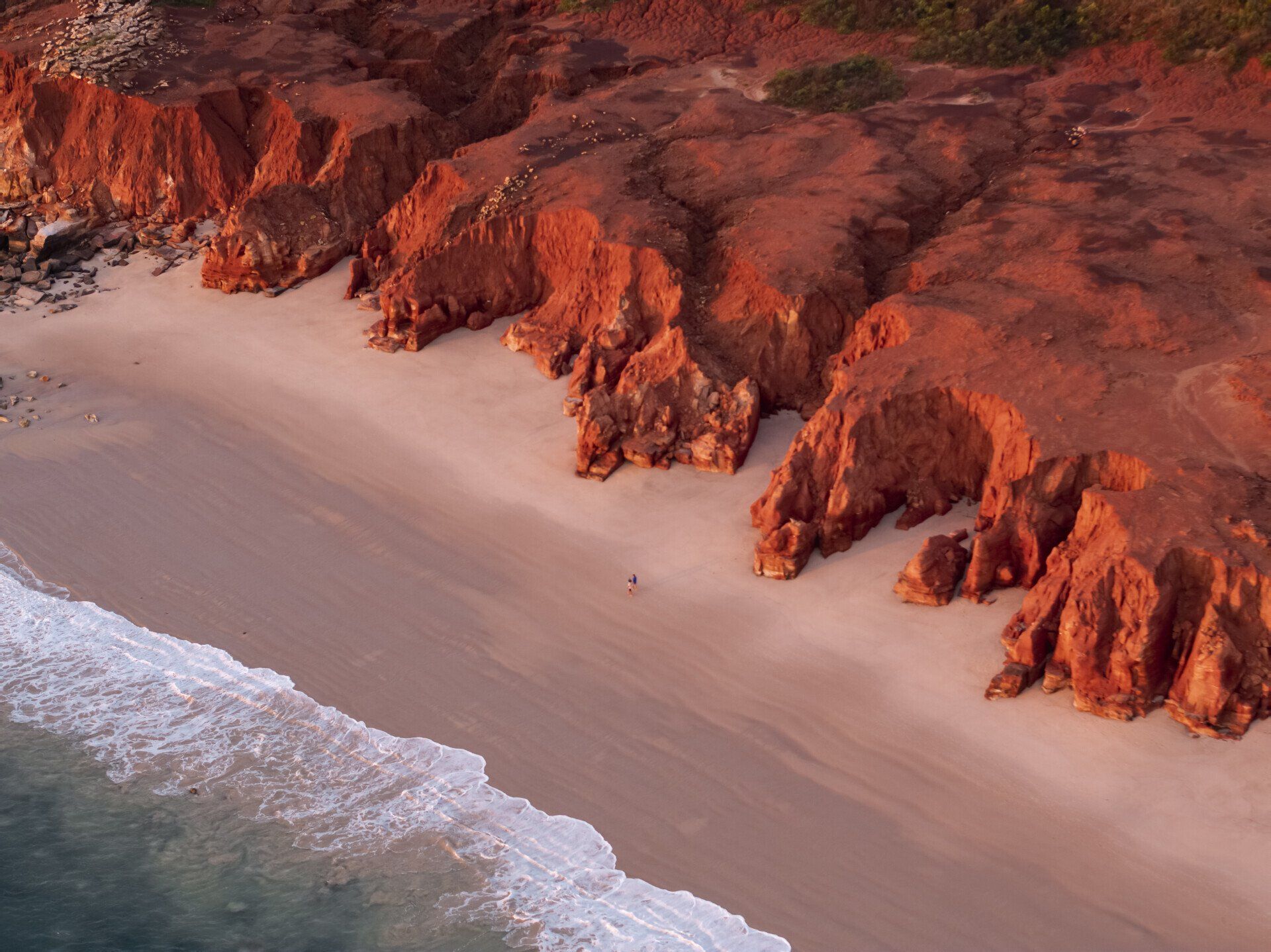 An aerial view of a beach with cliffs and waves