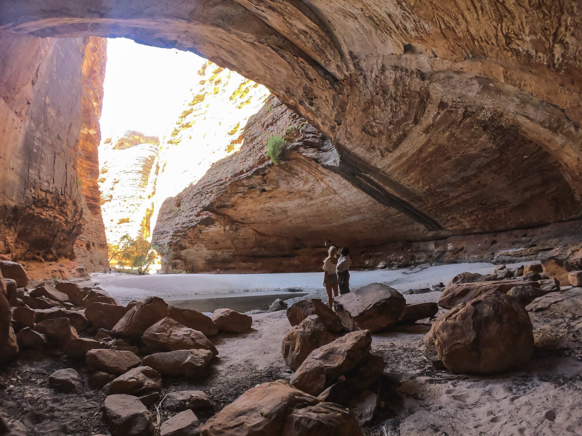 A couple standing in a cave with a river in the background.