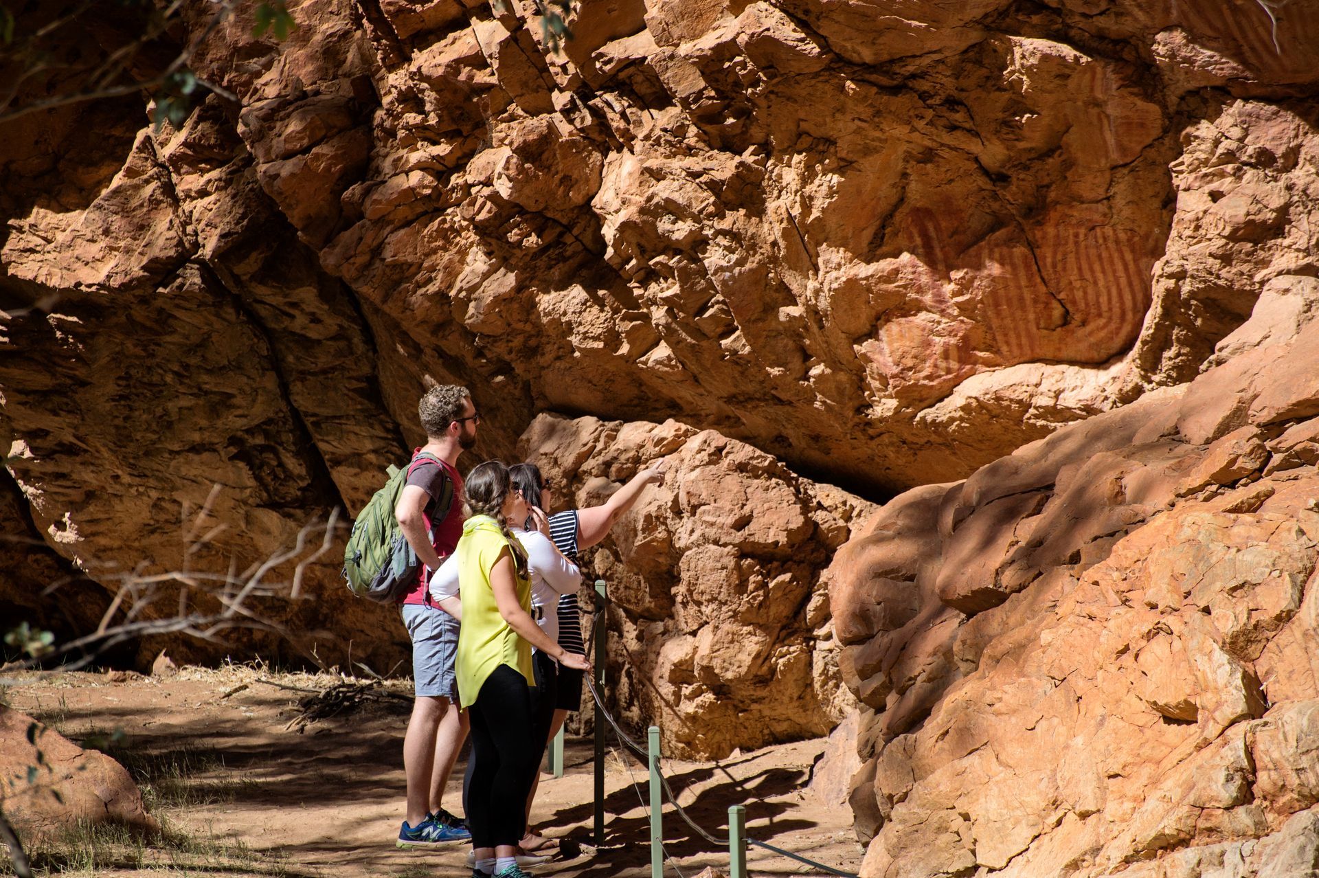 A group of people are standing in front of a large rock formation.