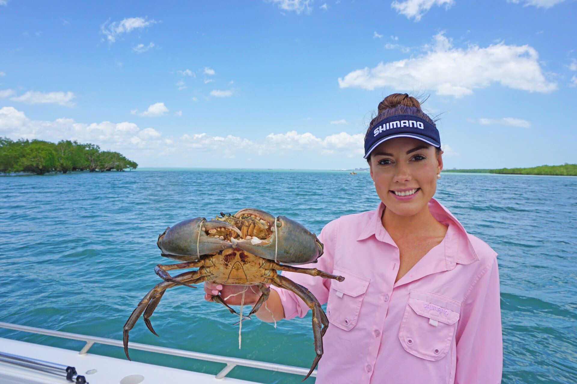 A woman is holding a large crab on a boat.