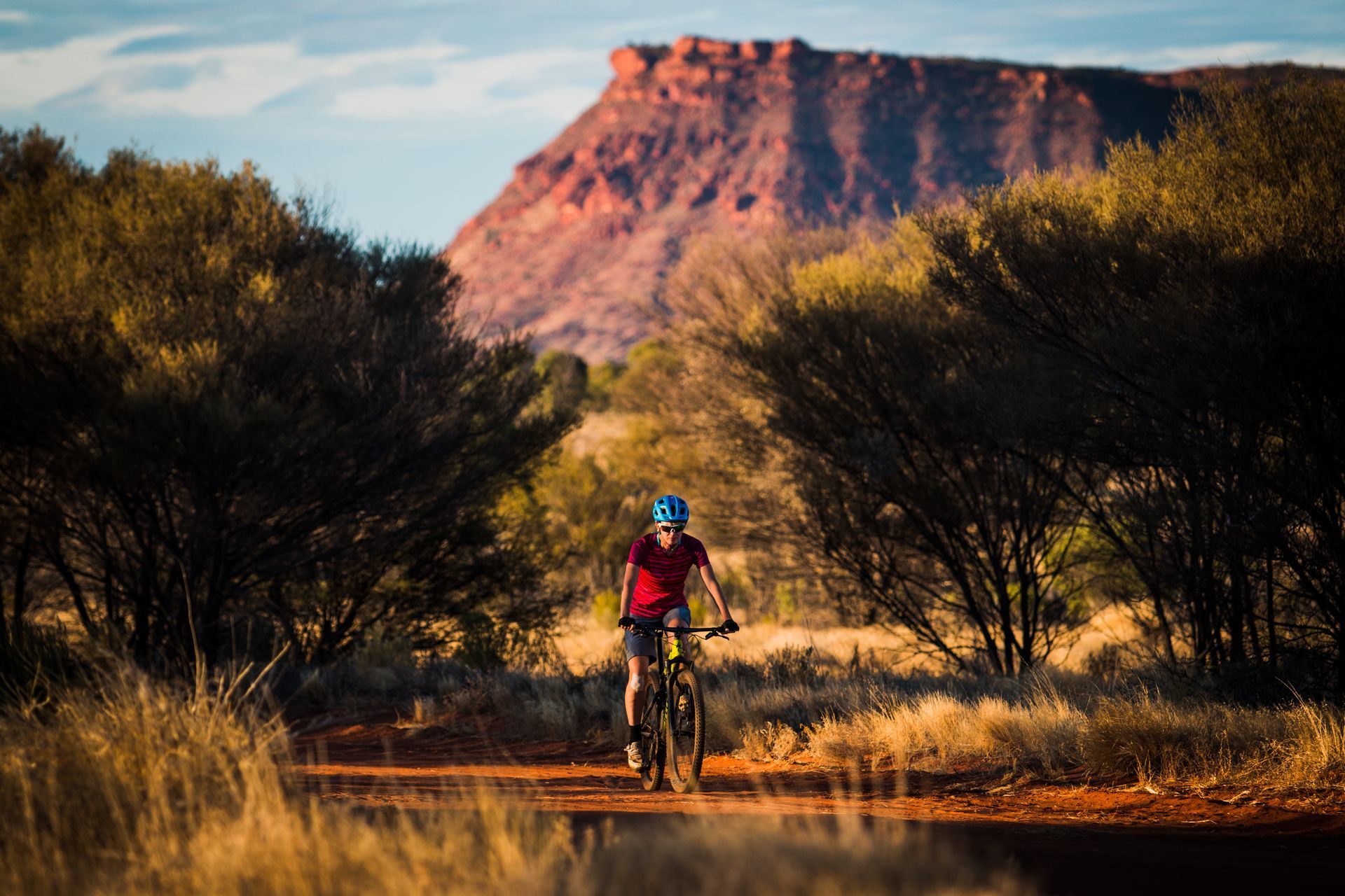 A man is riding a bike on a dirt road in the desert.
