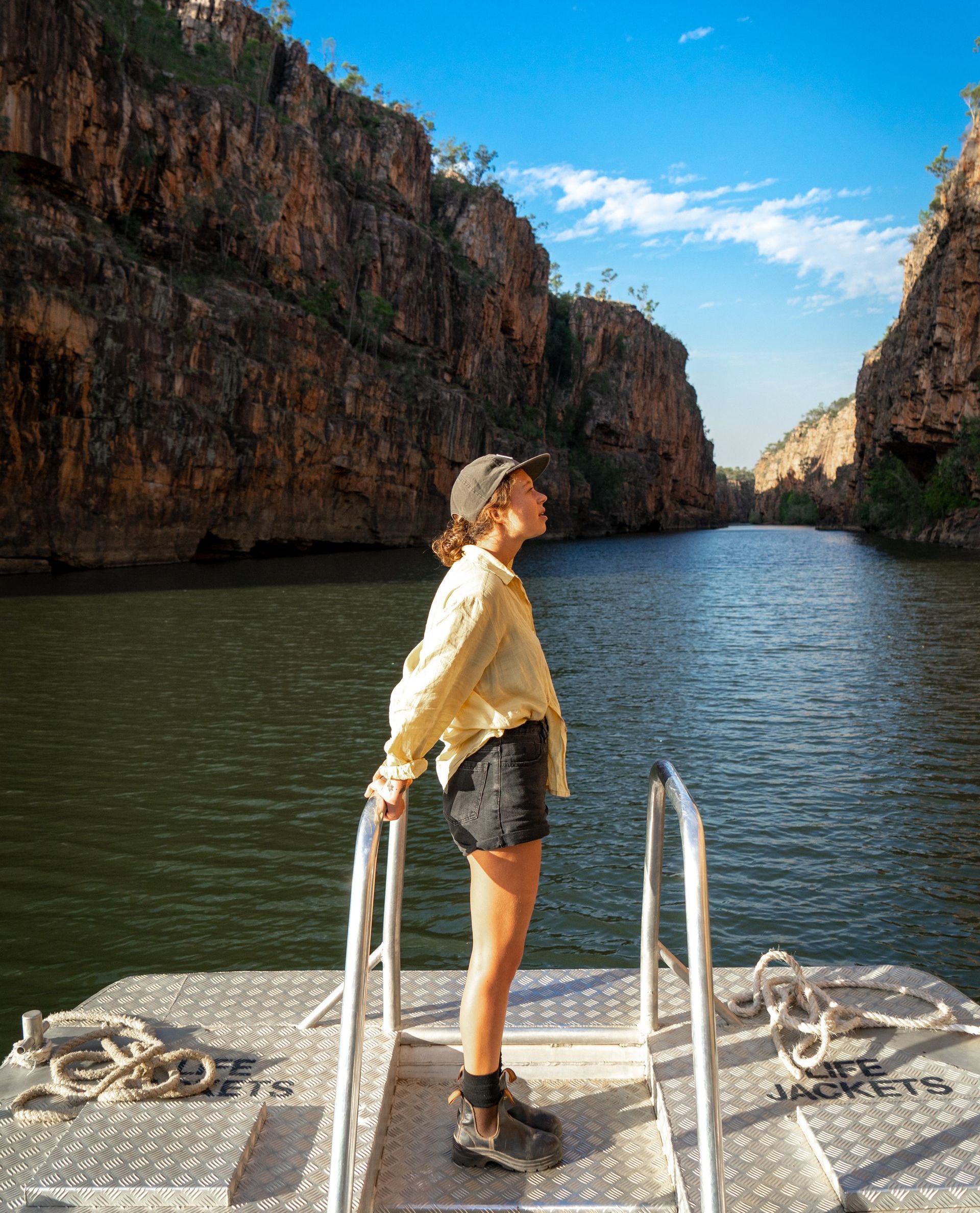 A woman is standing on a dock next to a body of water.