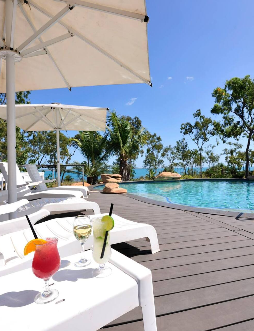 A swimming pool with umbrellas and a drink on a table