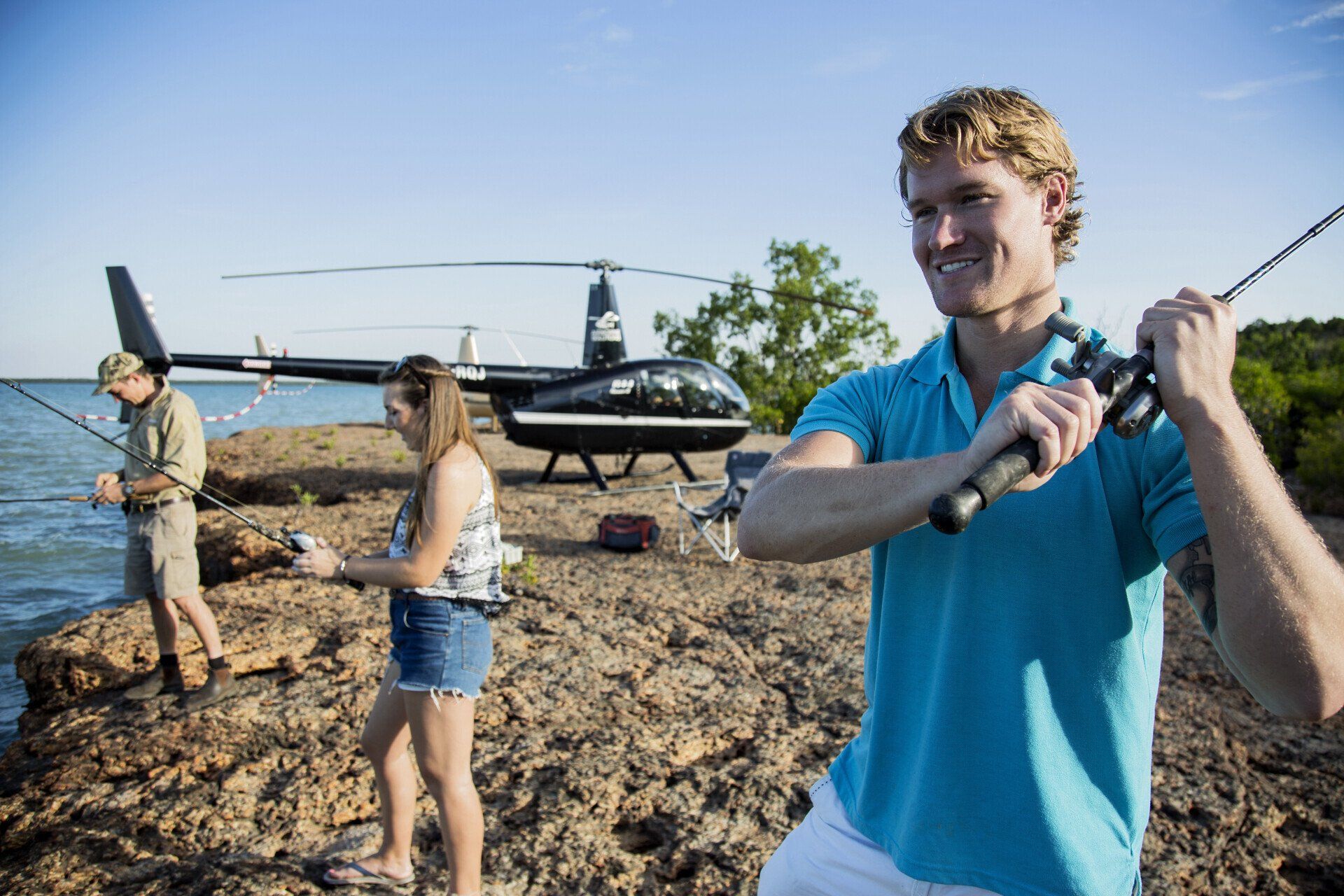 A man is holding a fishing rod in front of a helicopter.