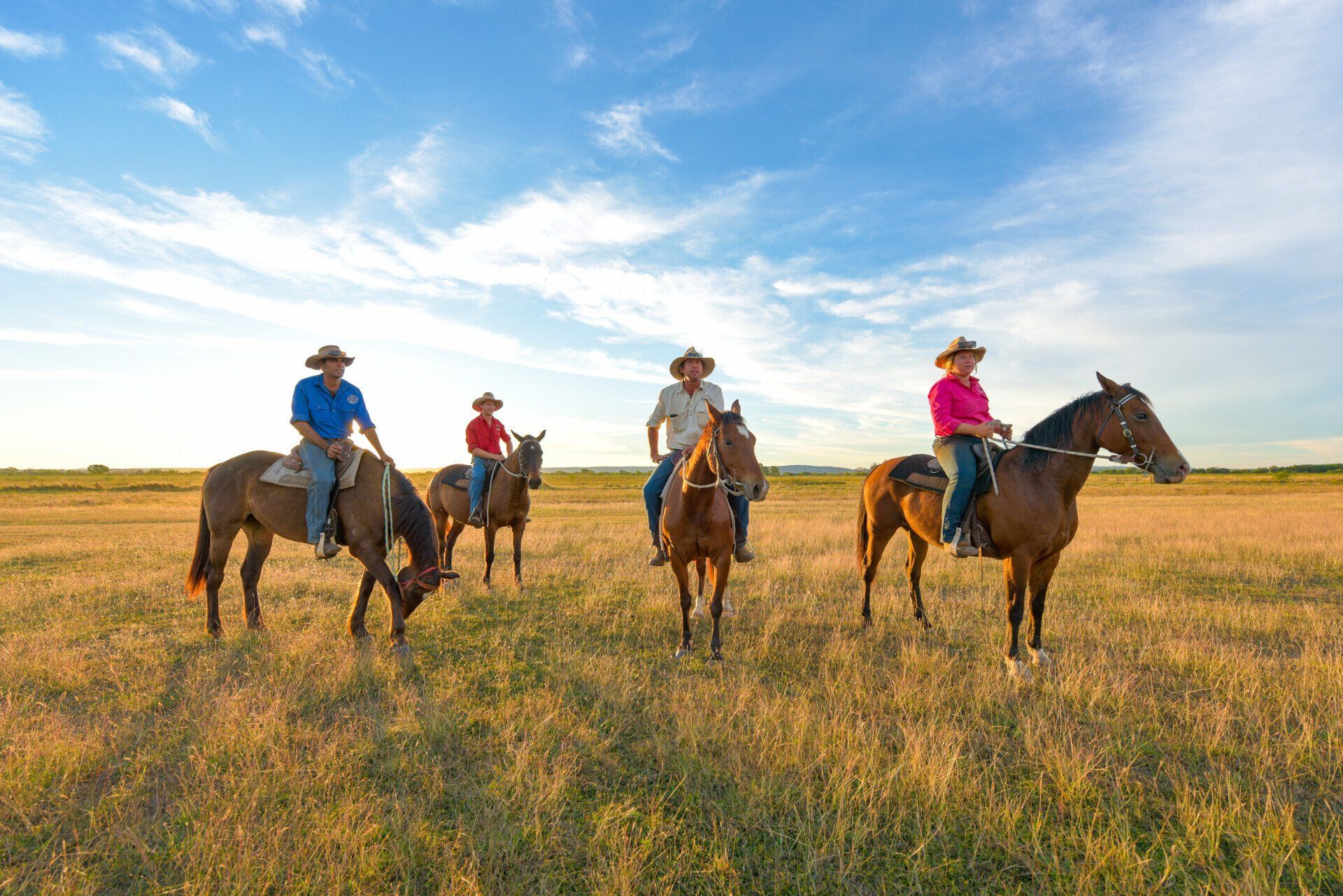 A group of people are riding horses in a field.
