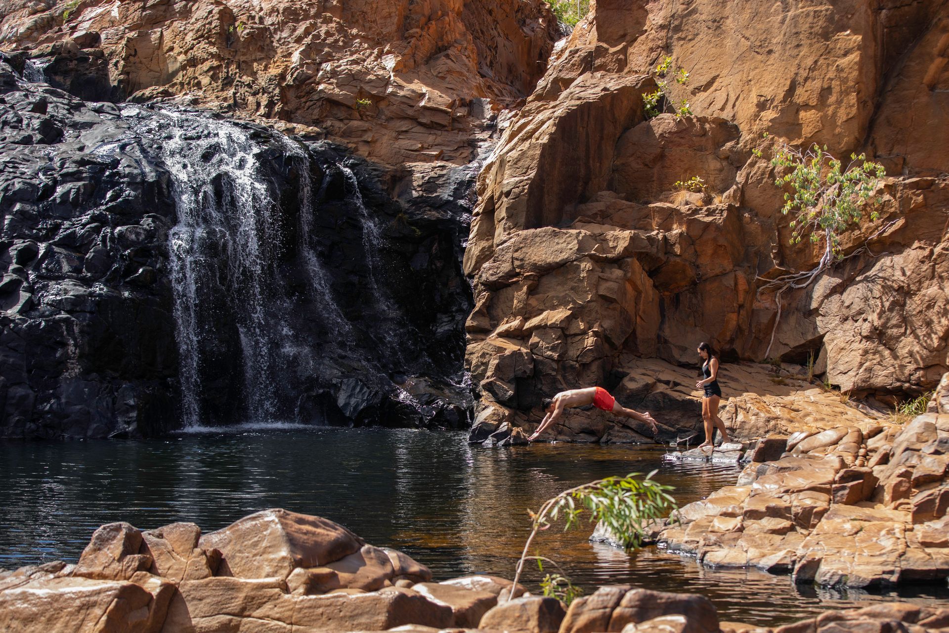 A waterfall is surrounded by rocks and a body of water