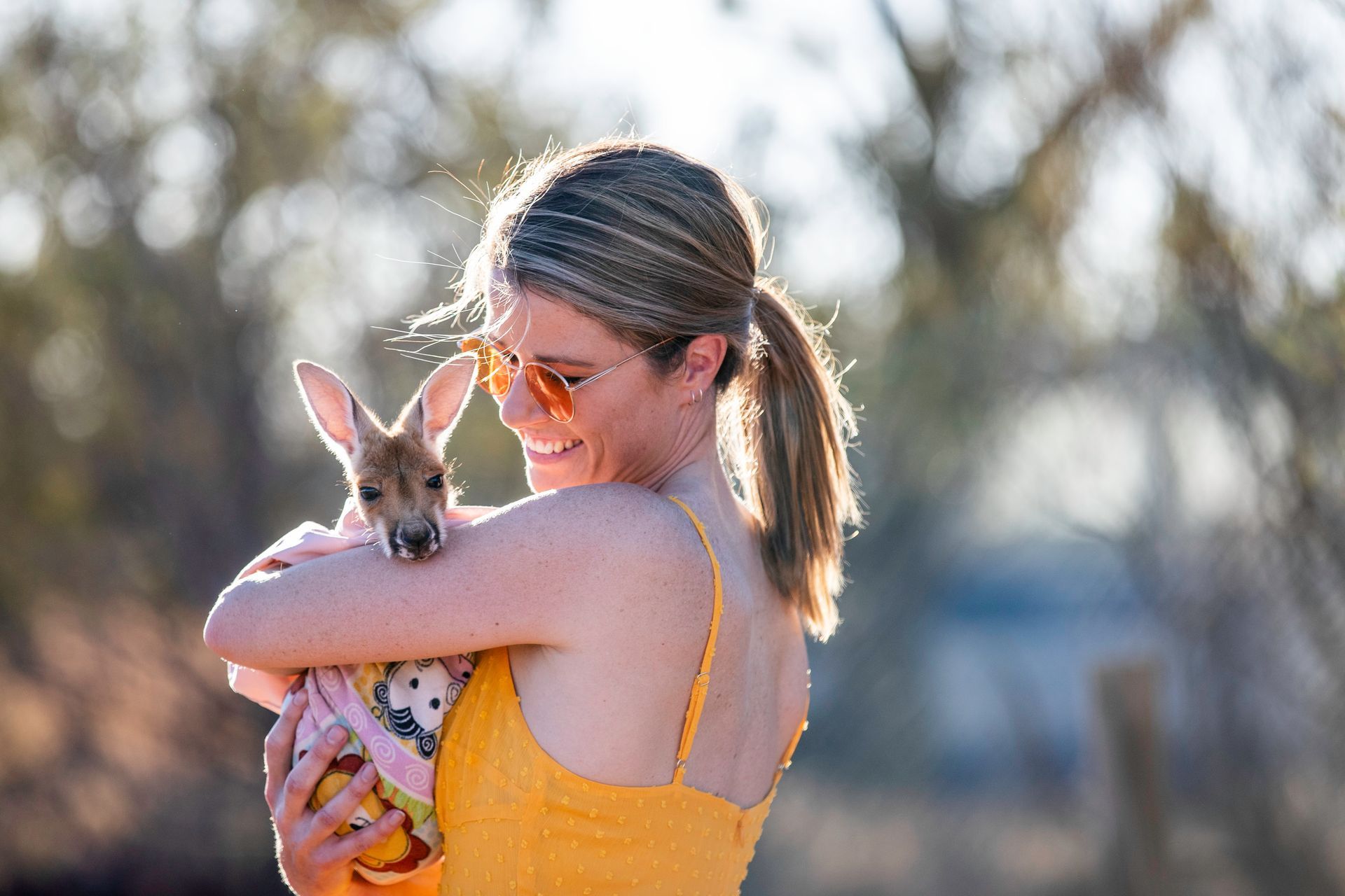 A woman is holding a kangaroo in her arms.