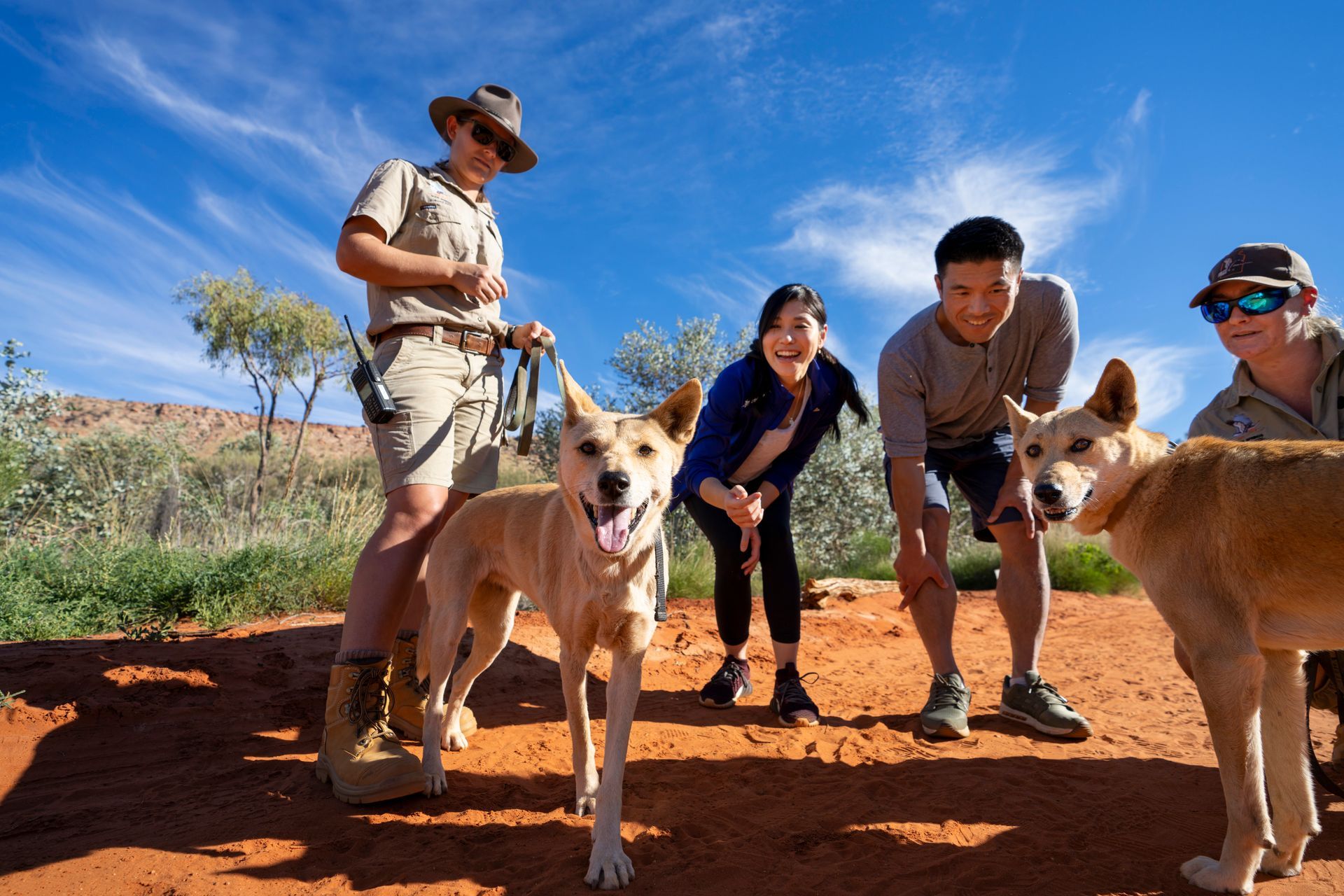 A group of people standing next to two dogs on a dirt road.