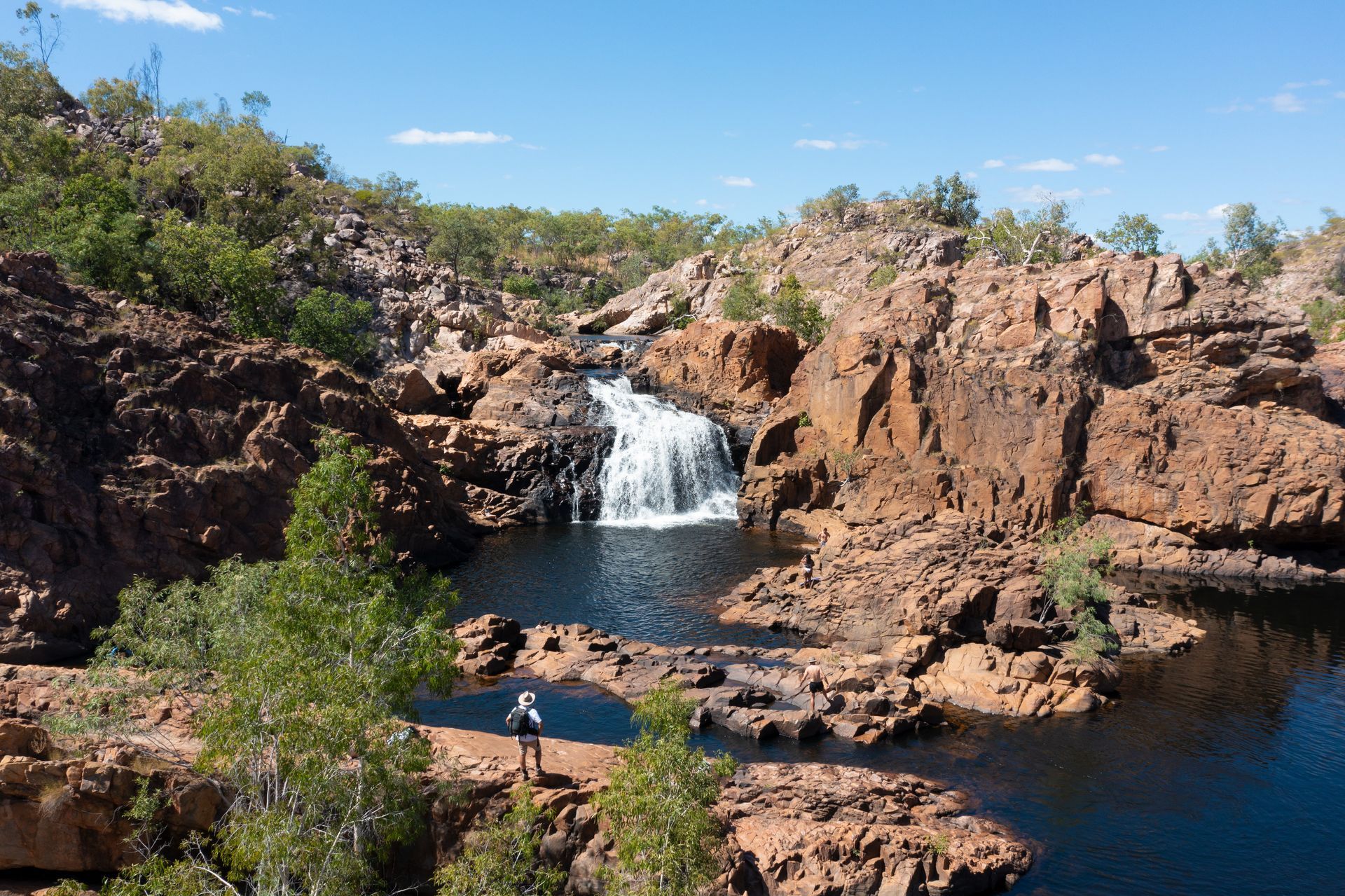 A person is standing on a rock near a waterfall.