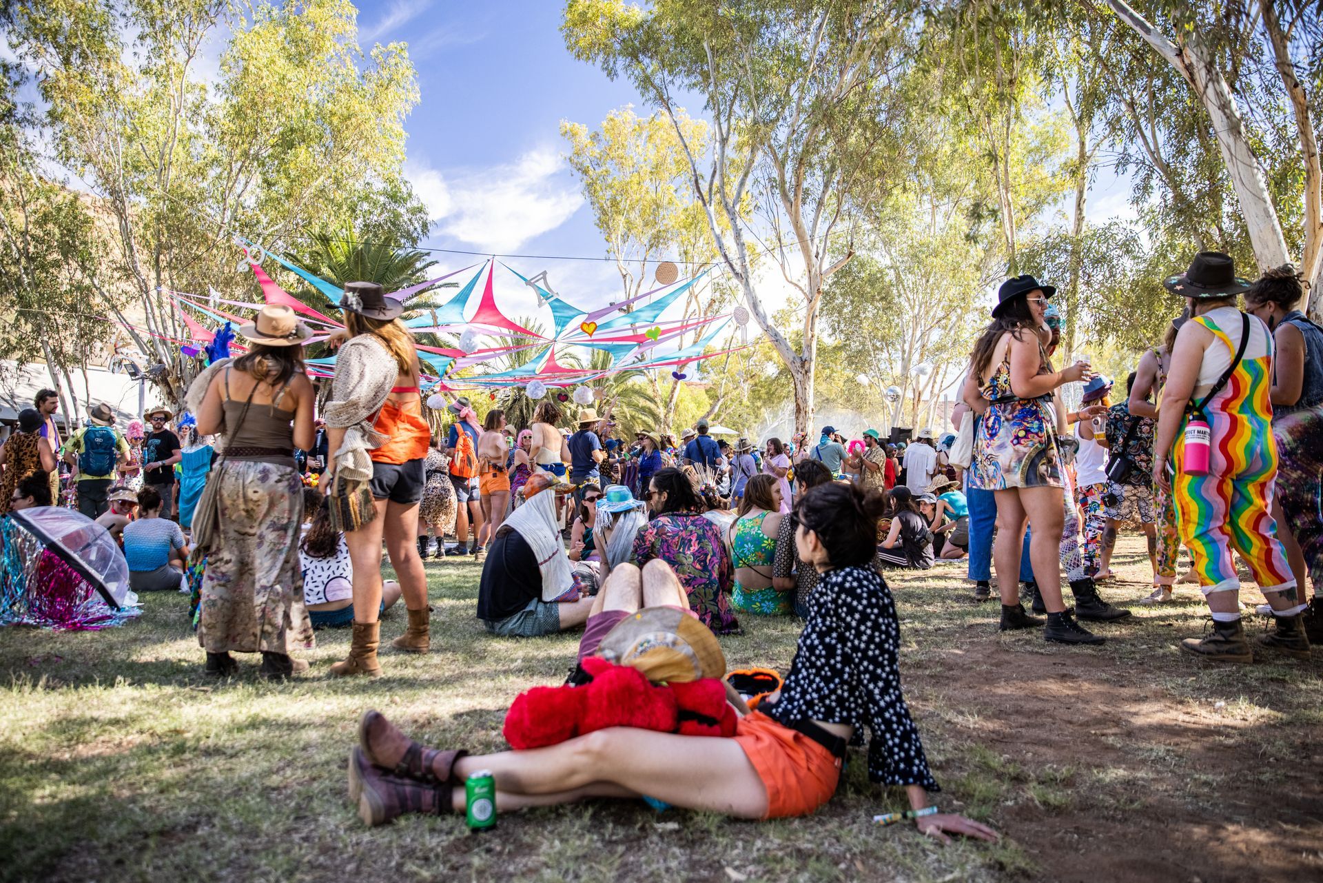 A group of people are sitting on the grass at a festival.