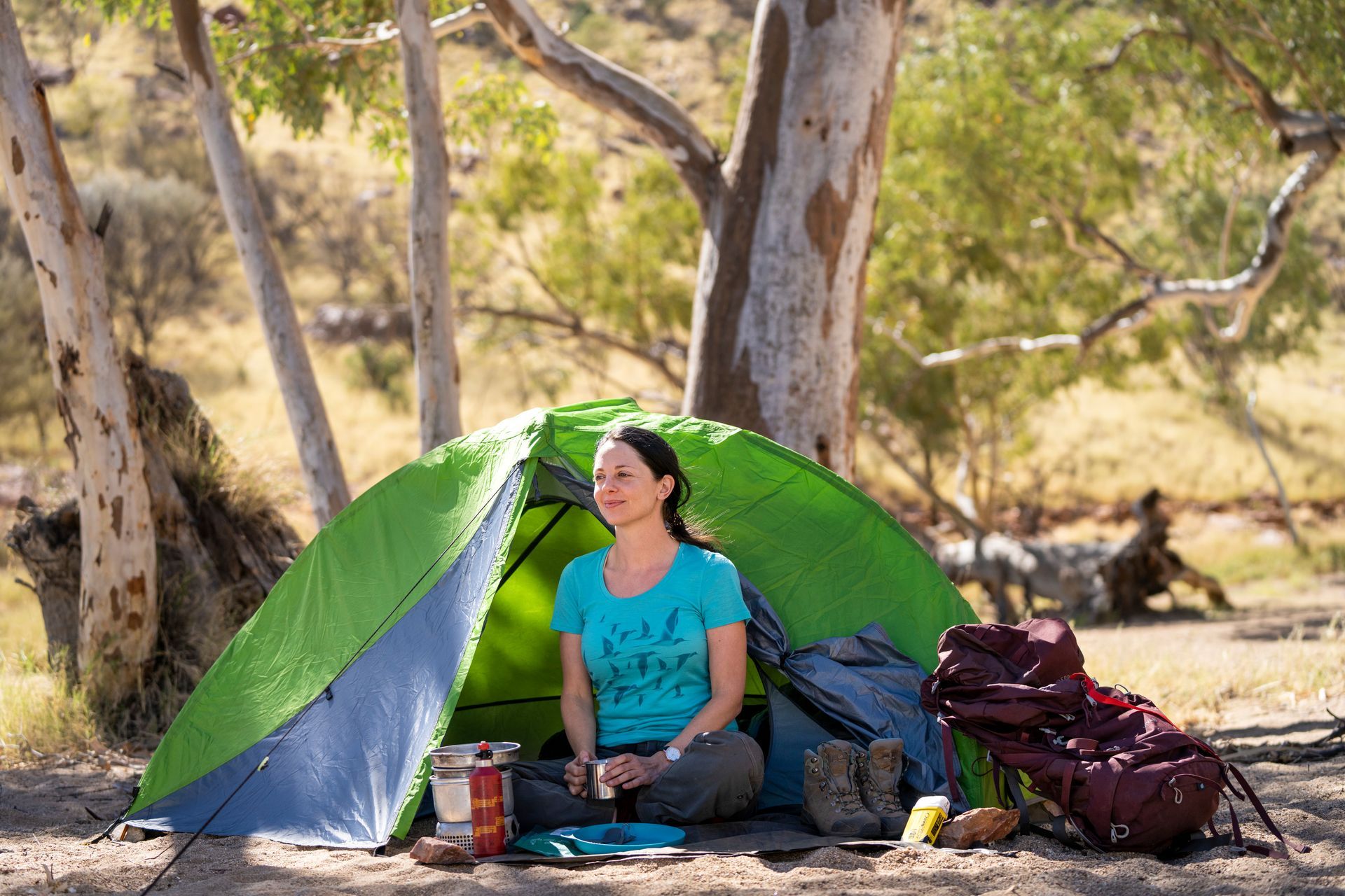 A woman is sitting in a tent under a tree.