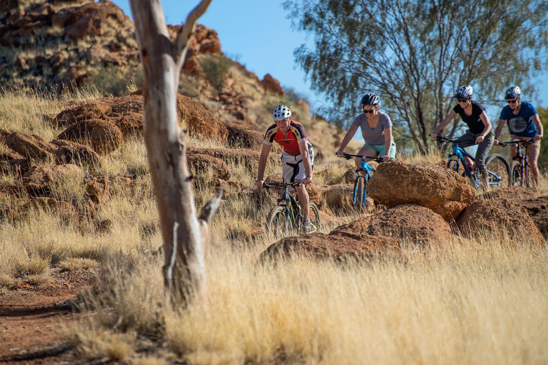 A group of people are riding bikes on a trail in the desert.