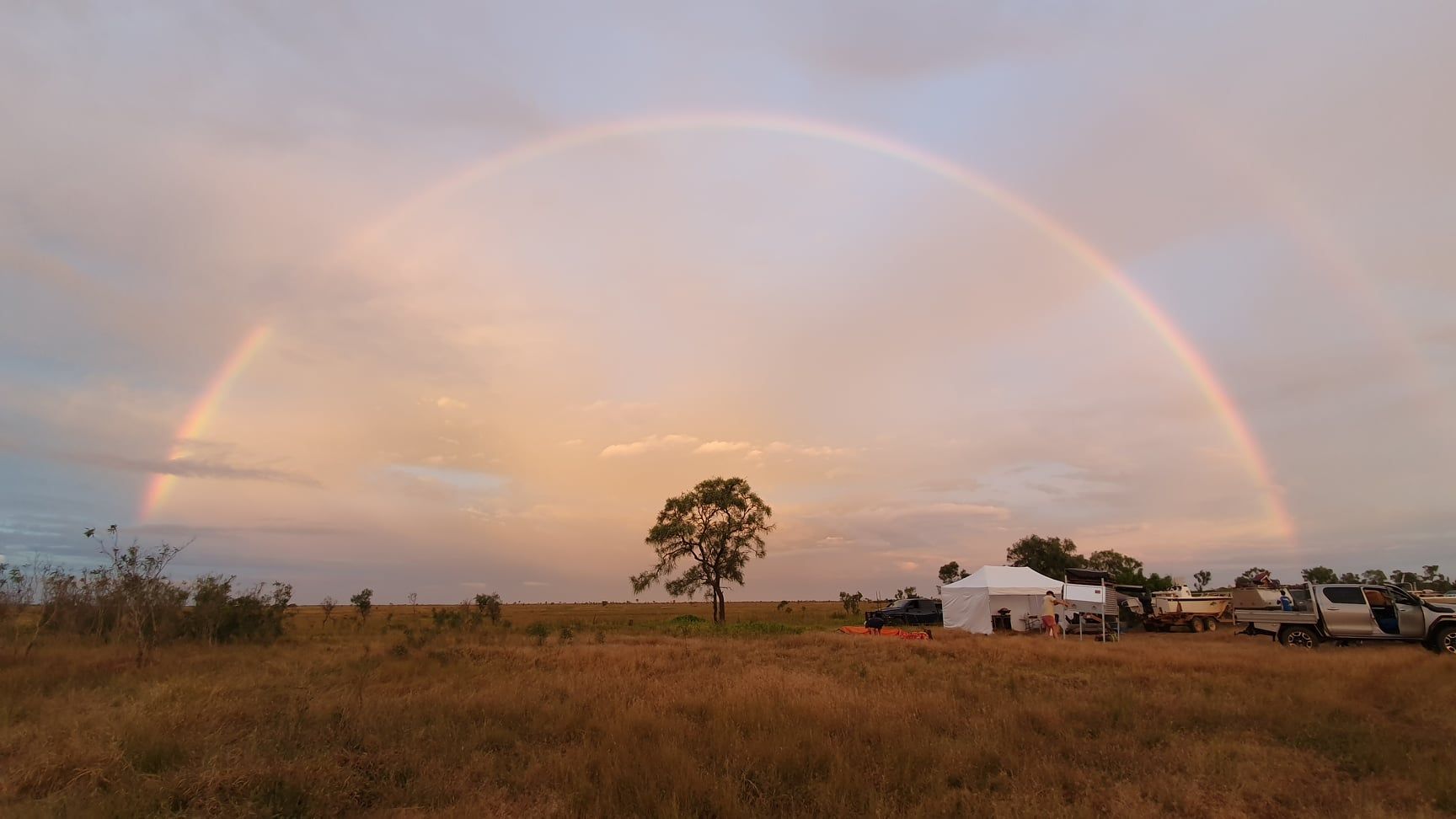 There is a rainbow in the sky over a field.