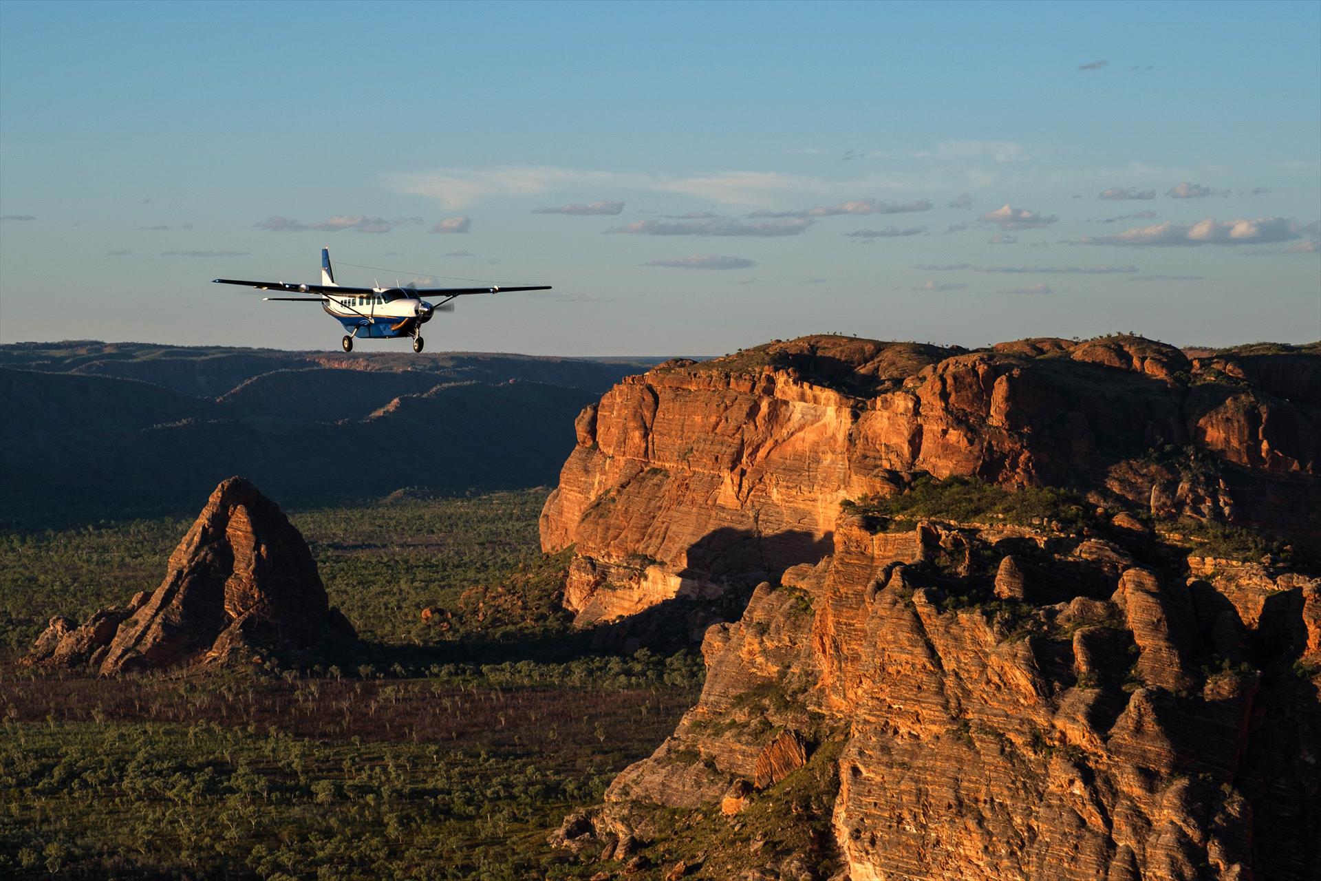 A small plane is flying over a mountain range.