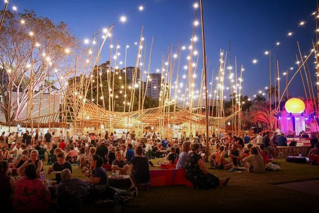 A large group of people are sitting under a tent with lights.