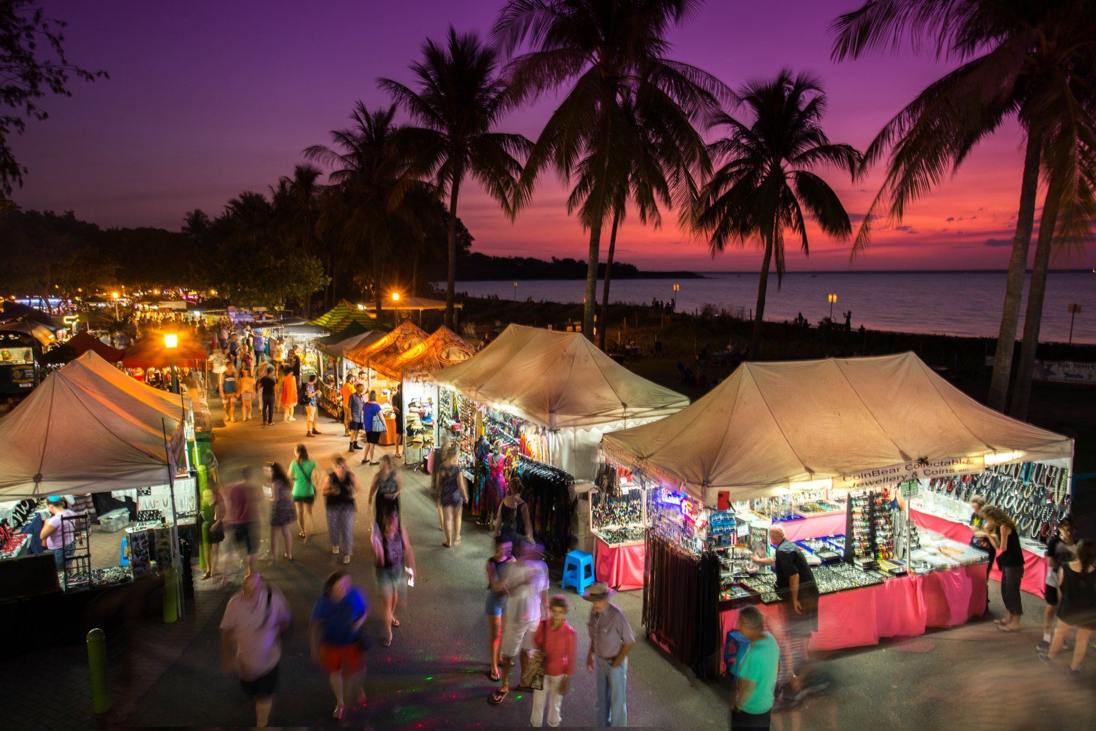 A group of people are walking around a market at night.