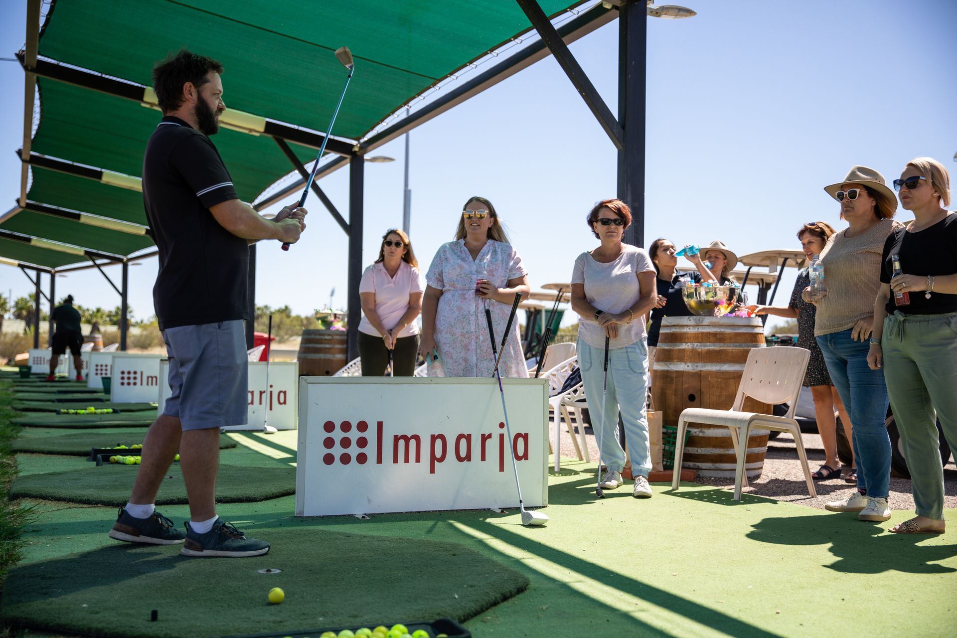 A man is teaching a group of people how to play golf.