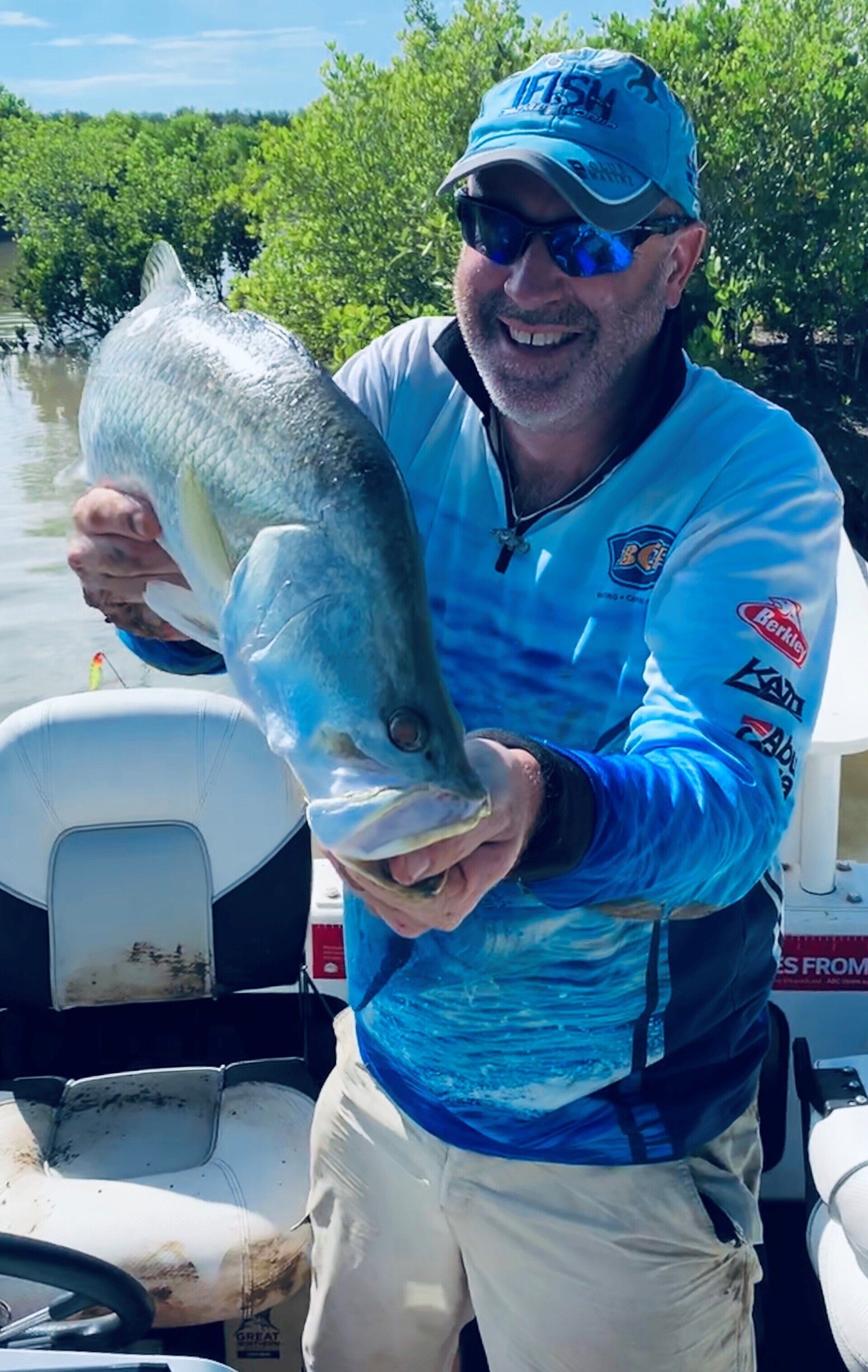 A man is holding a large fish in his hands on a boat.