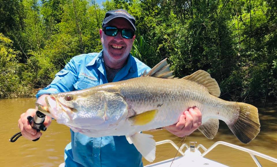 A man is holding a large fish in his hands on a boat.
