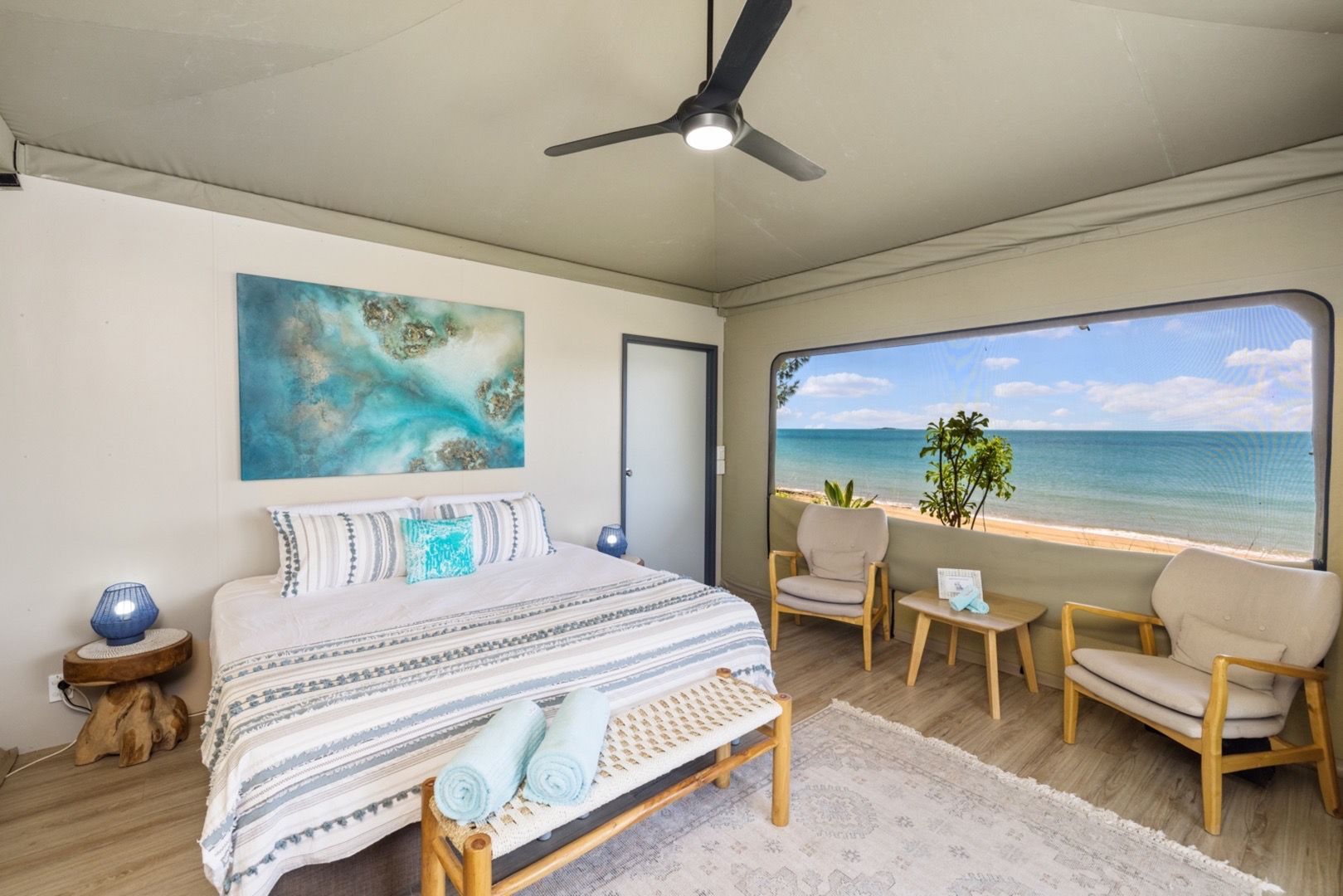 A bedroom with a bed , chairs , tables and a view of the ocean.