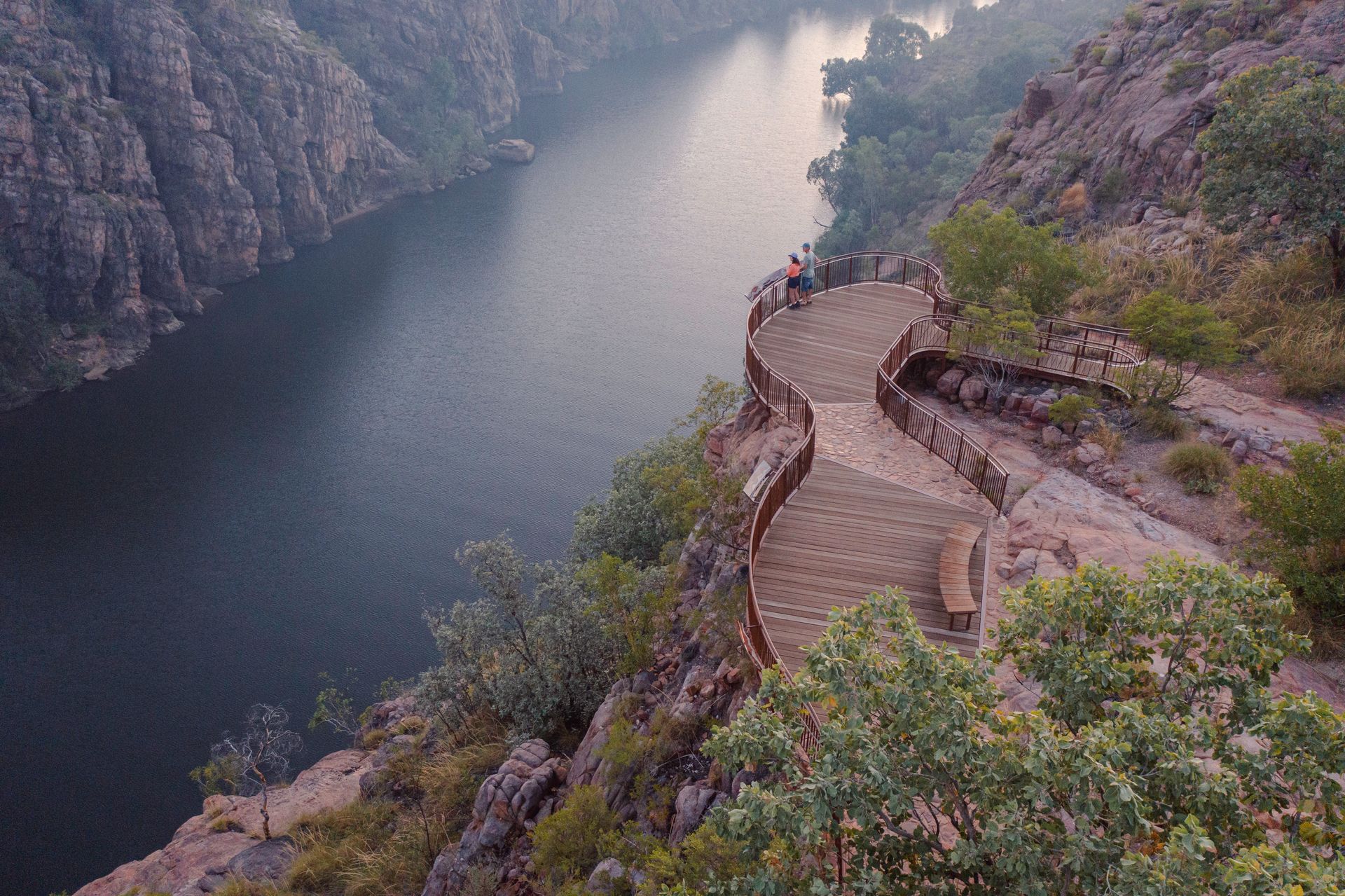 A river surrounded by mountains and trees with stairs leading to it