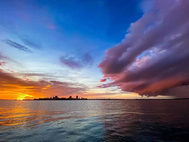 A sunset over a body of water with a cloudy sky