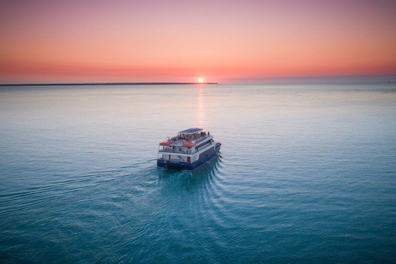 An aerial view of a boat in the ocean at sunset.