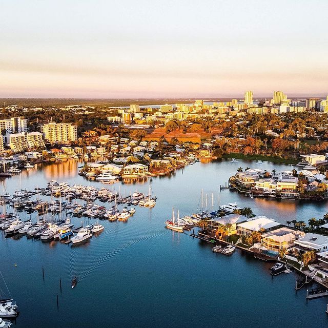 An aerial view of a marina filled with boats and a city in the background.