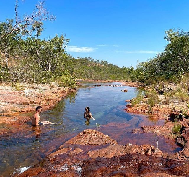 A man and a woman are swimming in a river.