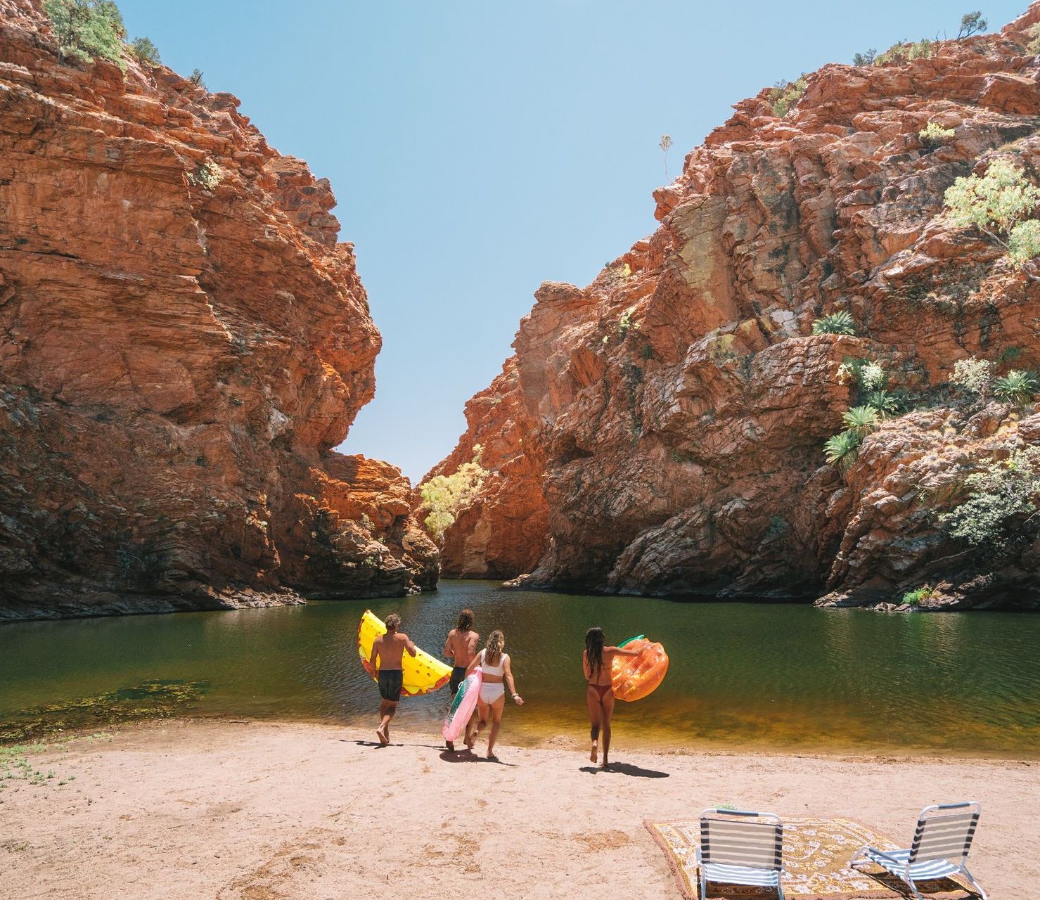 A group of people standing on a beach near a river