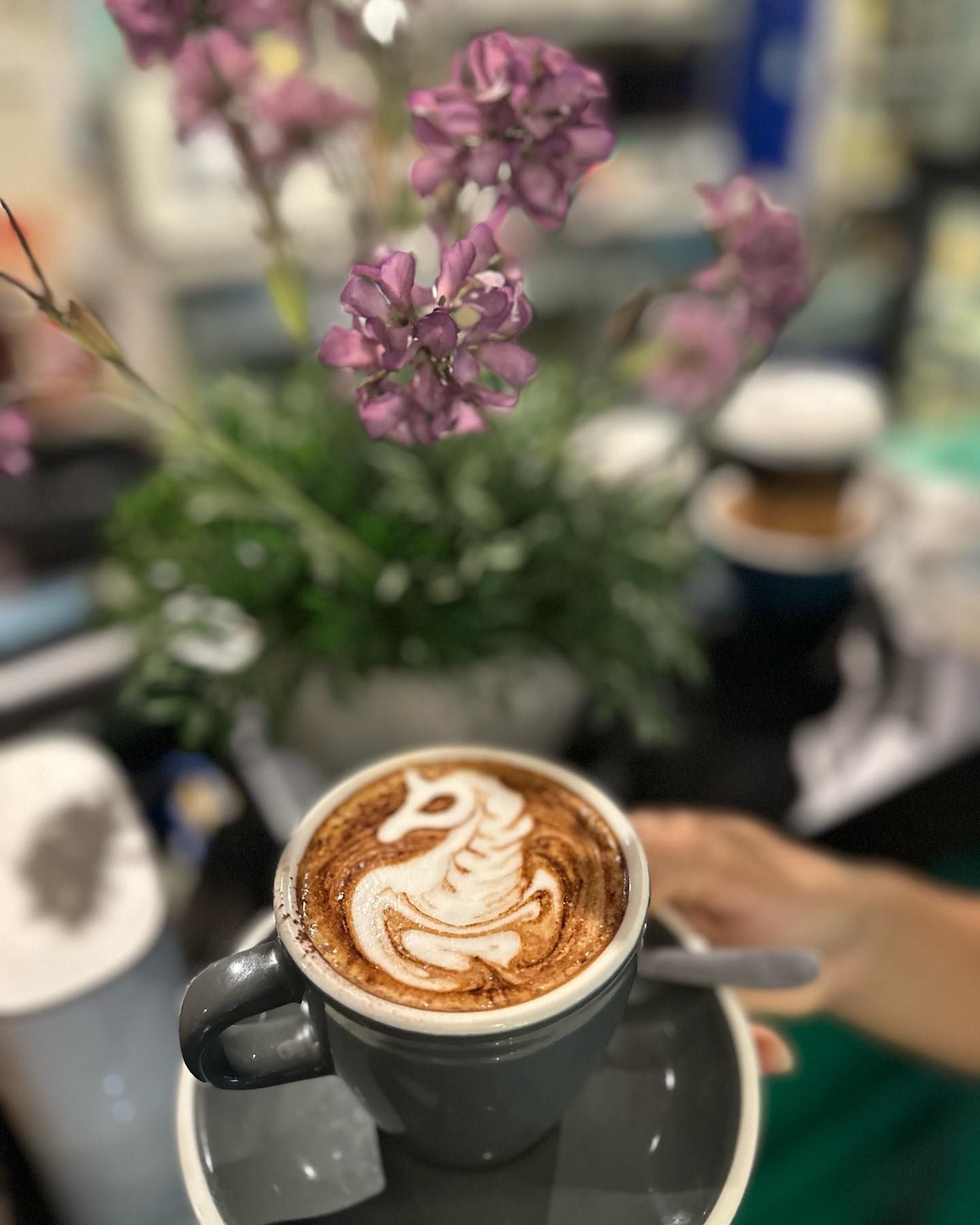 A person is holding a cup of coffee with a unicorn design on it.