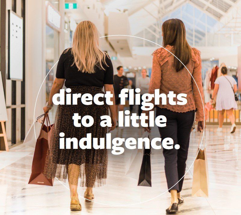 Two women are walking through a mall holding shopping bags.